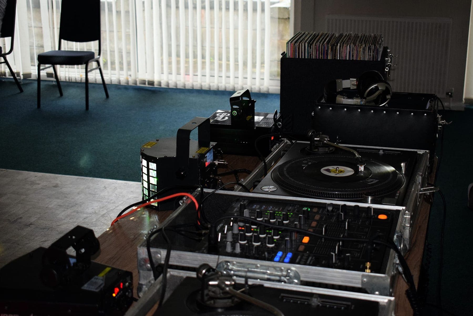 A vinyl DJ setup: two turntables, a mixer and a crate of records